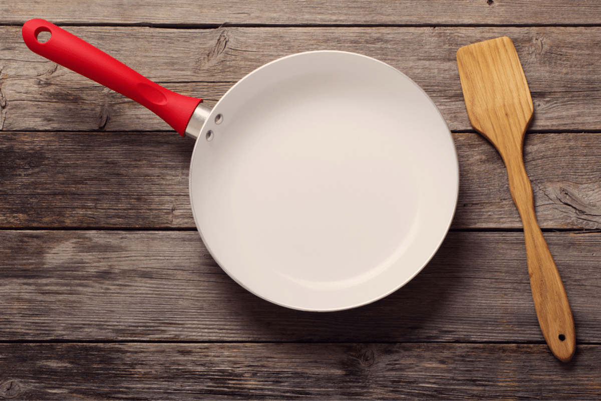 Come pulire la padella in ceramica per non danneggiarla illustrata con l'aiuto di una padella che si trova su un piano di legno