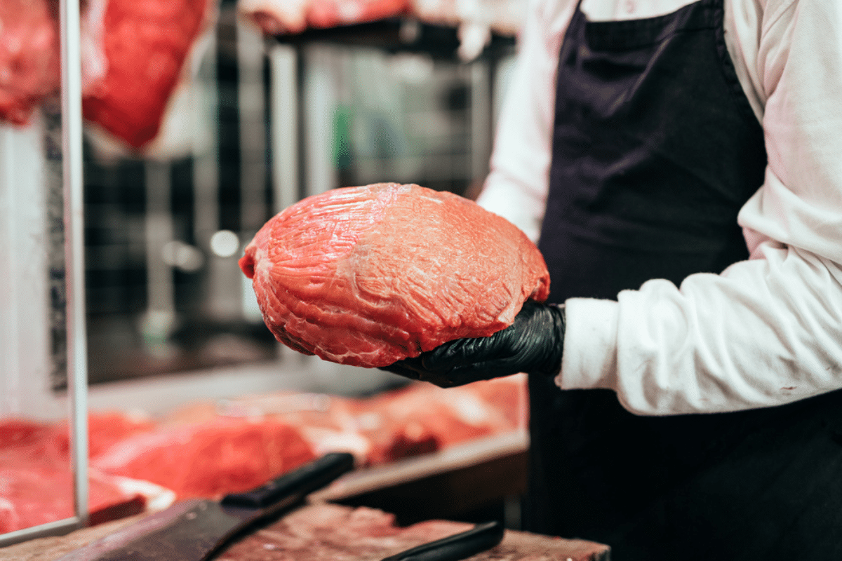 macellaio con in mano un pezzo di carne di manzo di qualità