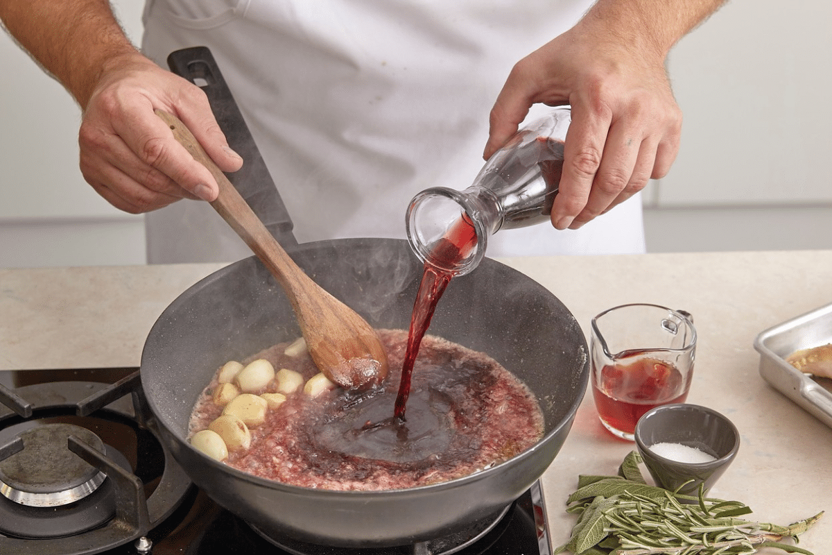 Persona che cucina con il vino mentre prepara una salsa